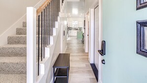 A modern interior with a staircase, a bench, and a kitchen area in the background. - Stylish OKC Duplex 2bed 2.5bath Unit B (Oklahoma City)