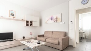 Una sala de estar moderna con un sofá, una mesa de centro, un televisor de pantalla plana y un estante en la pared.