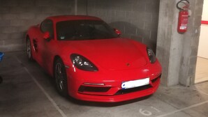 Un auto deportivo rojo estacionado en un estacionamiento de hormigón.