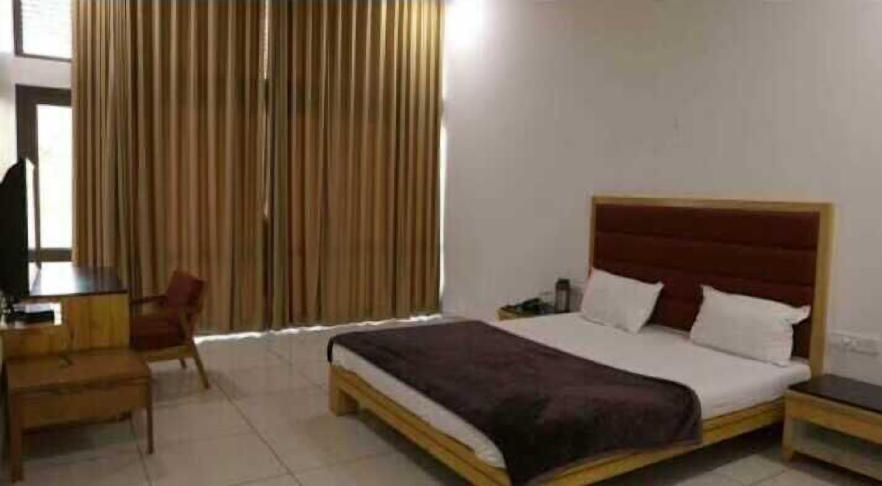 A bedroom with a bed, a desk, a chair, and a TV.
