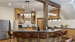 Une cuisine moderne dotée d’un îlot central, de meubles en bois et de tabourets de bar.