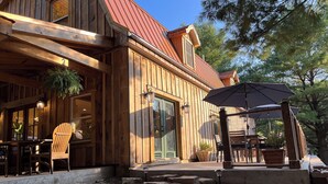 Een houten chalet met een rood dak, een veranda met stoelen en een pad van stenen dat naar de ingang leidt.