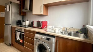 A compact kitchen with a built-in washing machine, a refrigerator, and a microwave. - Modern spacious apartment, direct access to London Bridge and central London (London)