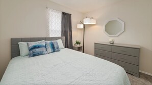 A bedroom with a bed, a dresser, a nightstand, a lamp, and a mirror. - Spacious 4-bedroom townhome with Cable and WiFi in charming Sanford (Sanford)