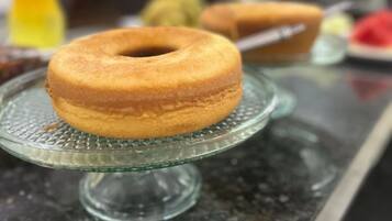 Uma bancada de cozinha com um suporte de vidro para bolo, exibindo um bolo.
