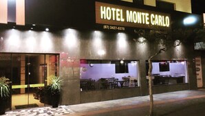 The exterior of Hotel Monte Carlo with a signboard, entrance, and visible seating area inside. - HOTEL MONTE CARLO (Dourados)