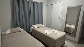 Un dormitorio con dos camas, un armario, un espejo y un equipo de aire acondicionado.