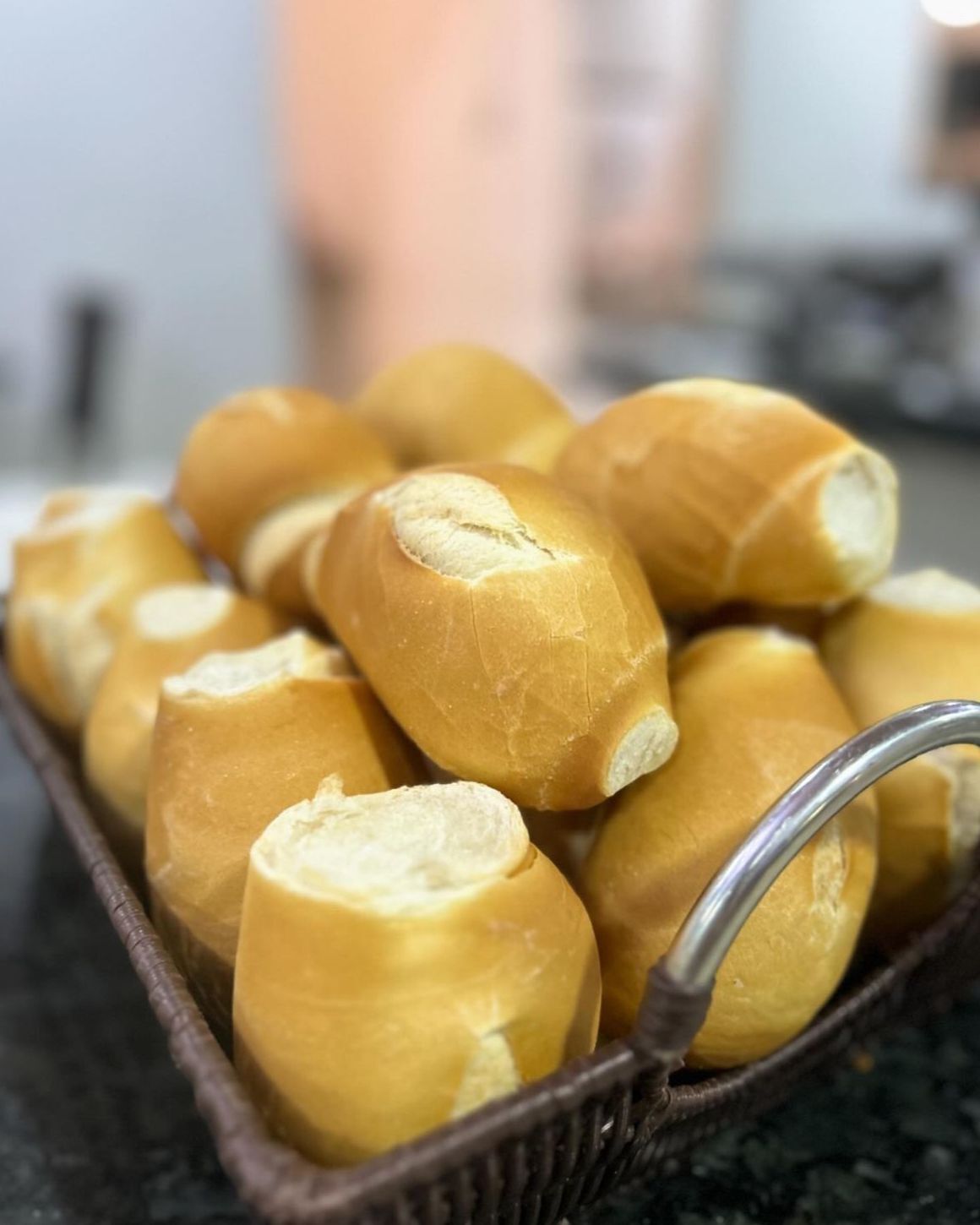 A basket of golden-brown buns with a metal handle.
