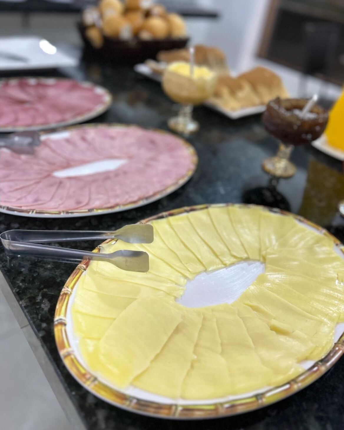 Un bancone da cucina con una torta grande, rotonda e gialla con centro bianco, una torta rosa e una torta marrone sullo sfondo.