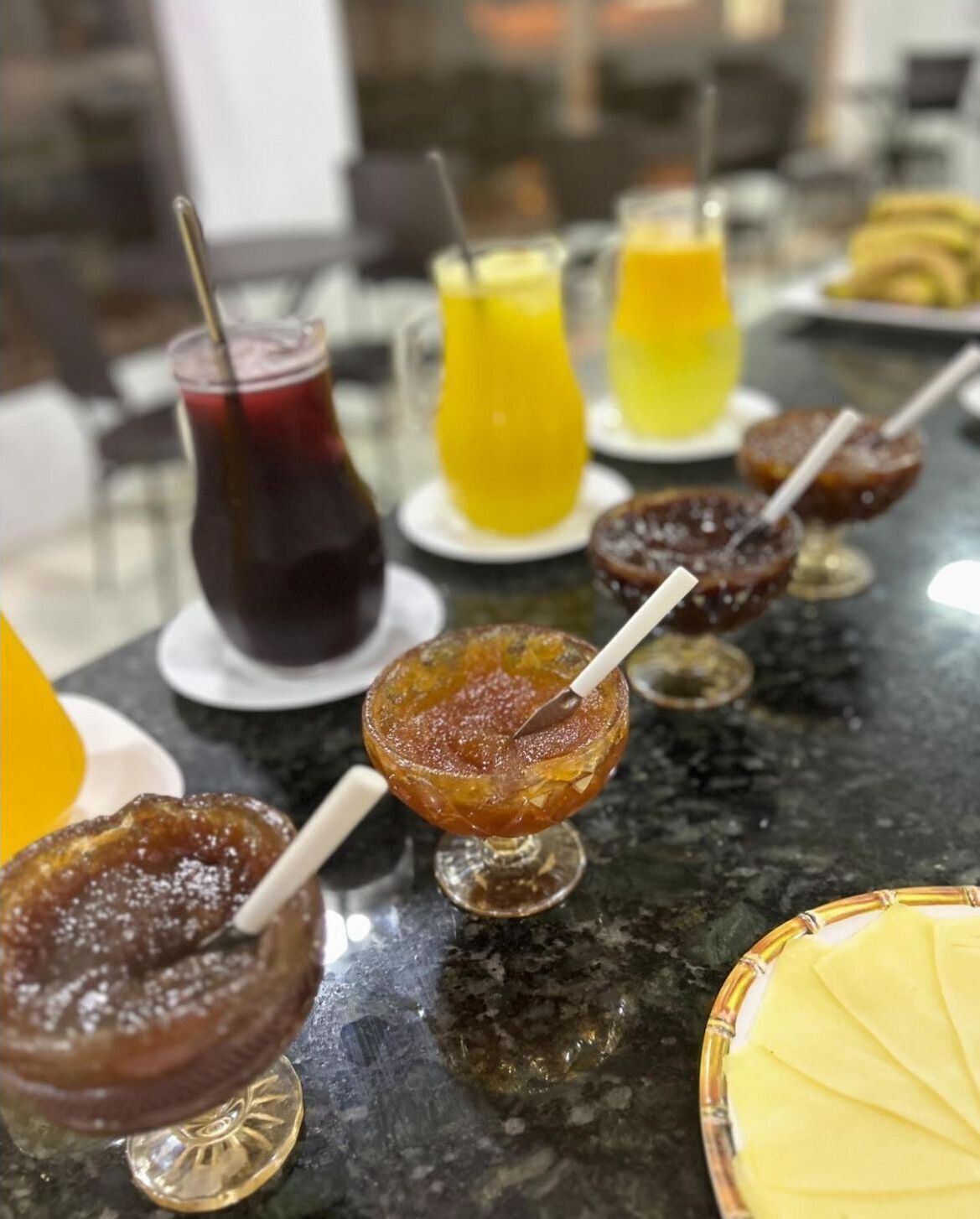 Uma área de bar com diversas bebidas, incluindo cocktails e sumos, servidas em diferentes copos.