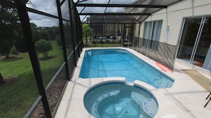 Ein Schwimmbad mit Whirlpool, umgeben von einer überdachten Terrasse mit Blick auf den Garten.