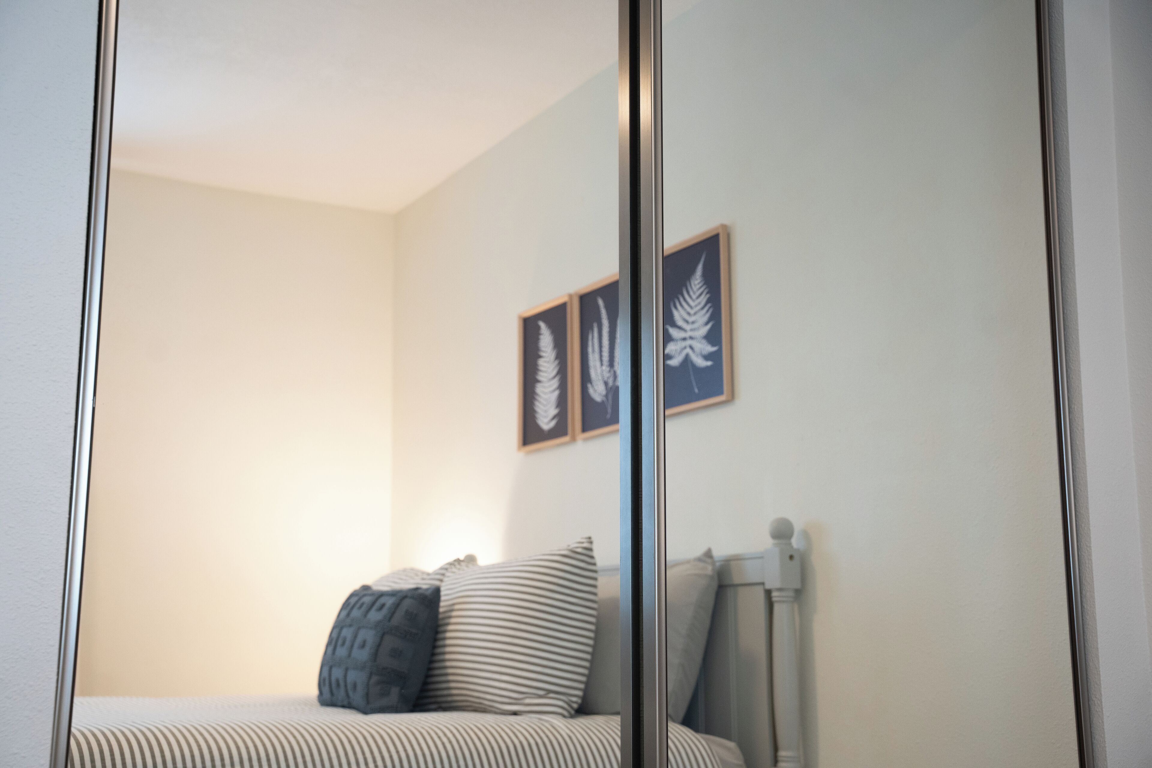 Une chambre à coucher avec un lit, des oreillers, un radiateur et des œuvres d’art encadrées accrochées au mur.