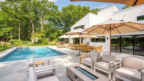 Un espace piscine comprenant un jacuzzi, des chaises longues et des parasols.