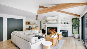 Un salon moderne avec une cheminée, un canapé, une table basse et un coin repas avec des chaises.