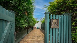 A narrow brick pathway leading to a gated entrance with a sign reading "533 Caroline The Bartlum". - The Bartlum Luxury Studio In Prime Location (Key West)