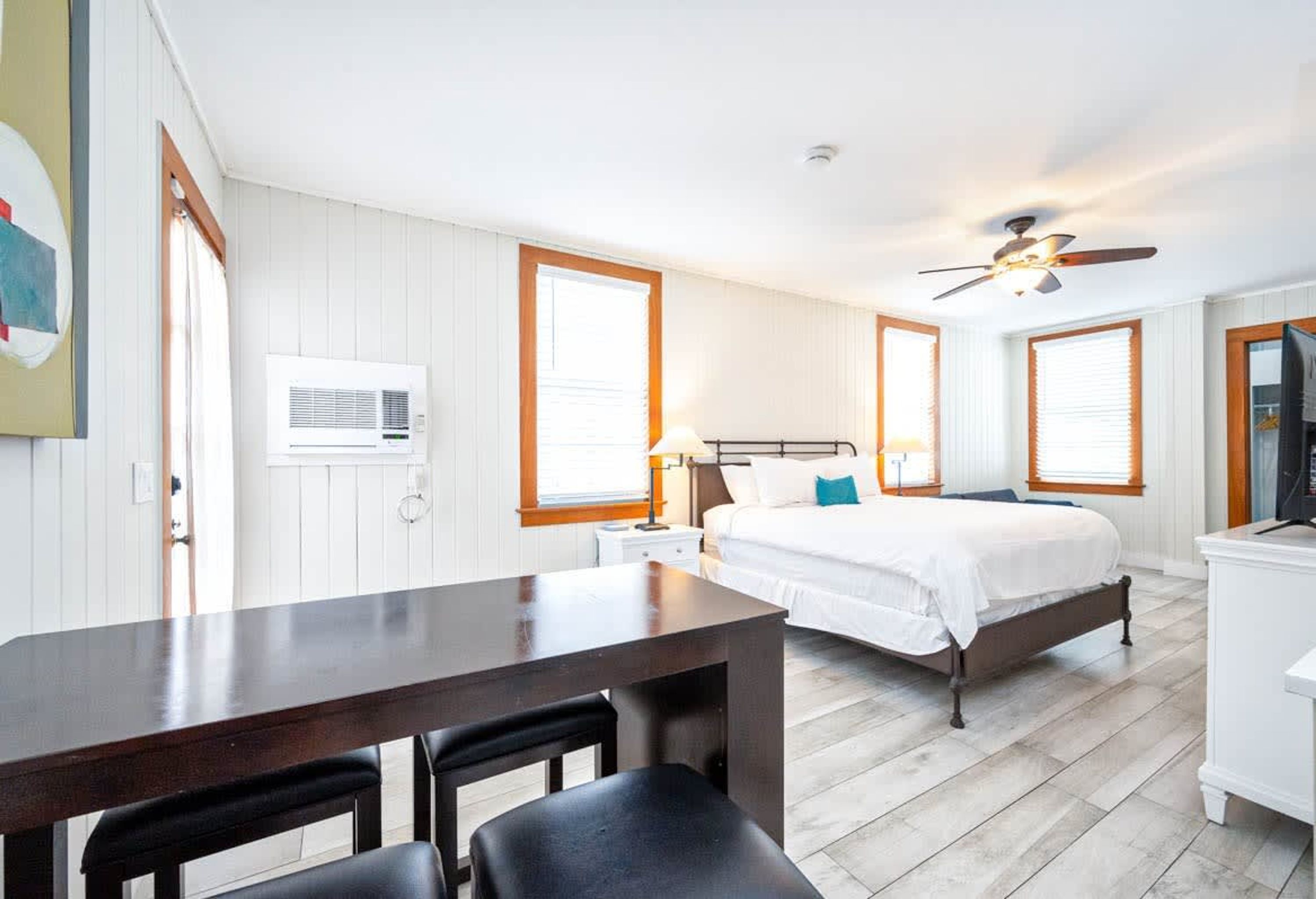 A bedroom with a bed, bedside table, lamp, and a ceiling fan.