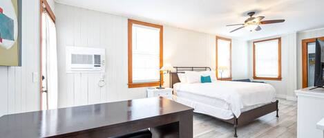 A bedroom with a bed, bedside table, lamp, and a ceiling fan.