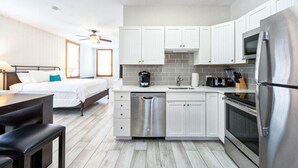 A modern kitchen with white cabinets, a stainless steel refrigerator, and a dishwasher. - The Bartlum Luxury Studio In Prime Location (Key West)