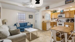 A living room with a sofa, a coffee table, and a dining table with chairs. There is a kitchen area with cabinets and appliances. - Sea Breeze by Brightwild Off-street Parking (Key West)