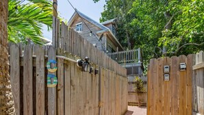 A wooden fence with a gate, a pathway, and a house in the background. - Sea Breeze by Brightwild Off-street Parking (Key West)