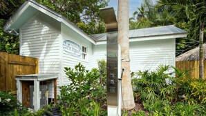 A white house with a sign reading "Life is Good" and a solar water heater. - Coconut Palm by Brightwild Island Home w Pool (Key West)