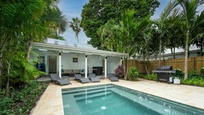 A backyard with a swimming pool, lounge chairs, and a barbecue grill. - Coconut Palm by Brightwild Island Home w Pool (Key West)