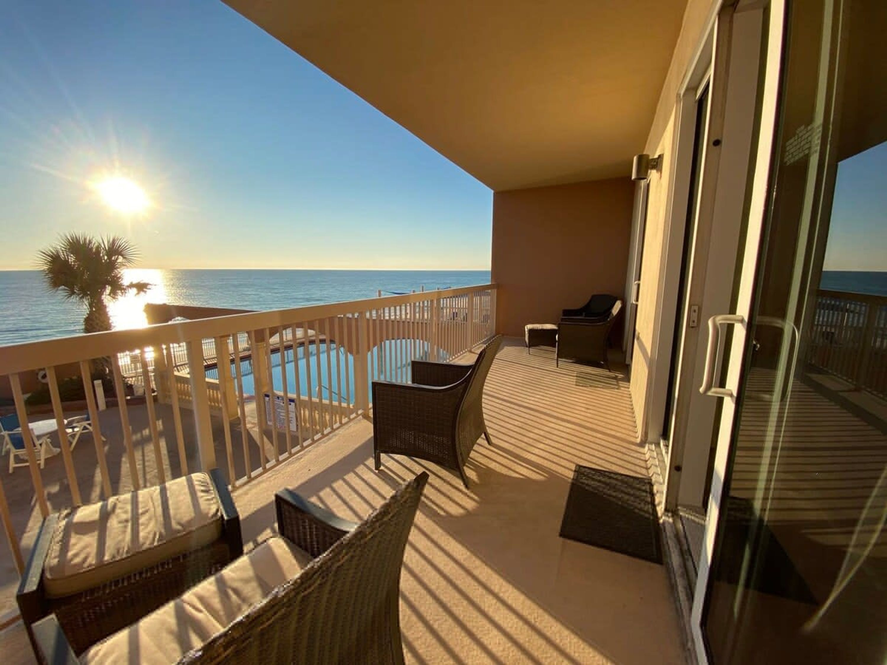 Een balkon met uitzicht op de oceaan, een zwembad en tuinmeubilair.
