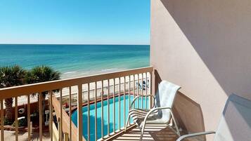 A balcony with a view of the ocean and a swimming pool.