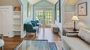 A spacious room with a high ceiling, a seating area with a sofa and chairs, a wooden coffee table, and a view through a glass door to the outdoors. - Sky Loft by Brightwild Penthouse in Prime Spot (Key West)