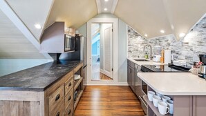 A compact kitchen with a wooden countertop, built-in appliances, and a stone backsplash. - Sky Loft by Brightwild Penthouse in Prime Spot (Key West)