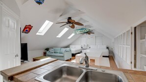 A spacious attic bedroom with a large skylight, a ceiling fan, and a kitchenette. - Southern Palms by Brightwild Pool Parking (Key West)
