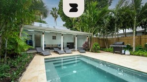 A backyard with a swimming pool, lounge chairs, a barbecue grill, and a wooden fence. - Southern Palms by Brightwild Pool Parking (Key West)