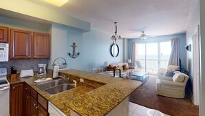 A spacious kitchen with granite countertops, wooden cabinets, and a dining area with a sofa and coffee table. - Coastal Condo 807 by Brightwild Beachfront (Panama City Beach)