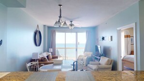 A room with a large window, a ceiling fan, a dining table, and a bed. - Coastal Condo 807 by Brightwild Beachfront (Panama City Beach)