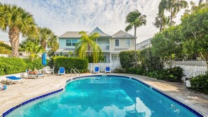 A swimming pool with lounge chairs, palm trees, and a white picket fence. - Gulf Getaway by Brightwild Condo w Pool (Key West)