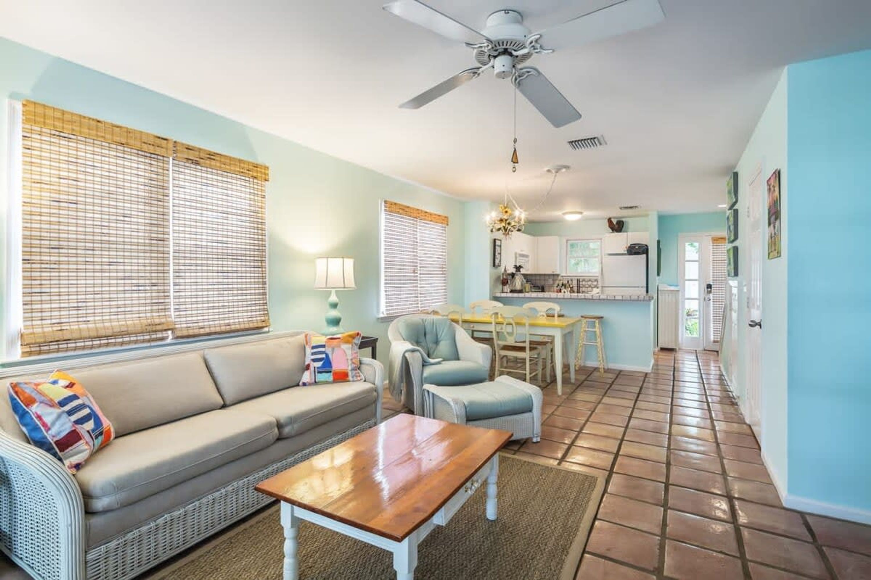 A living room with a sofa, coffee table, and a dining area with chairs and a table.