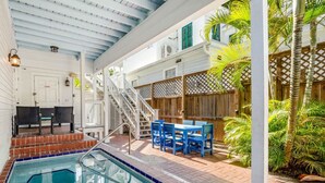 A pool area with a tiled deck, a wooden fence, and outdoor furniture. - Bananas Foster by Brightwild Epic Guesthouse (Key West)