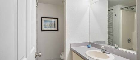 Une salle de bain avec un lavabo blanc, un miroir et un sol à carreaux noirs et blancs.