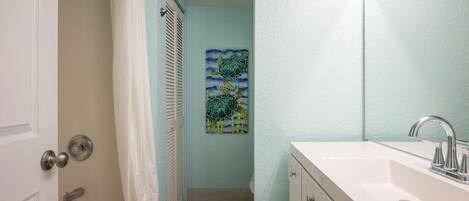 A bathroom with a white sink, a shower curtain, and a towel on the floor.