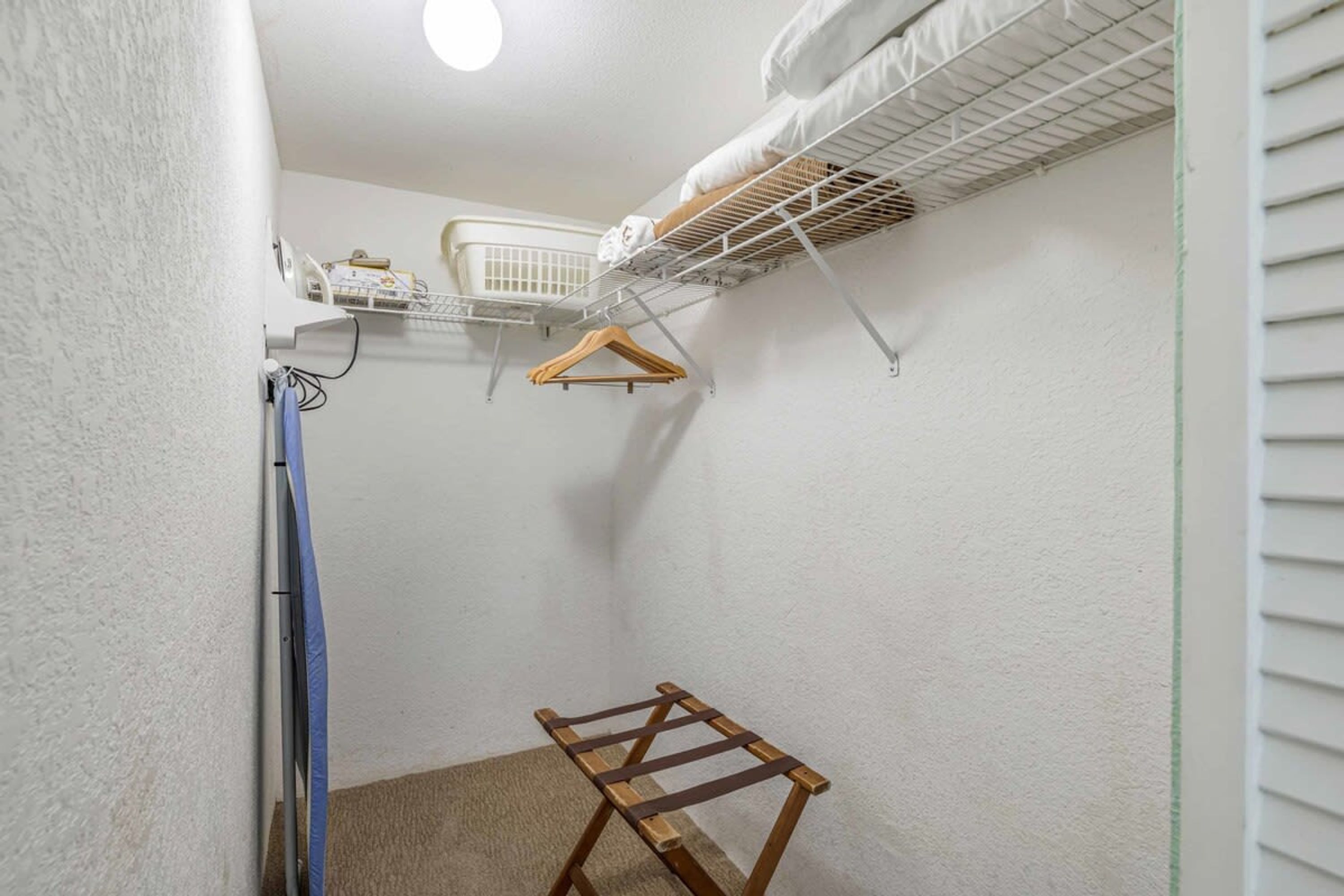 A small, narrow room with a white wall, a wooden drying rack, and a white ceiling fan.