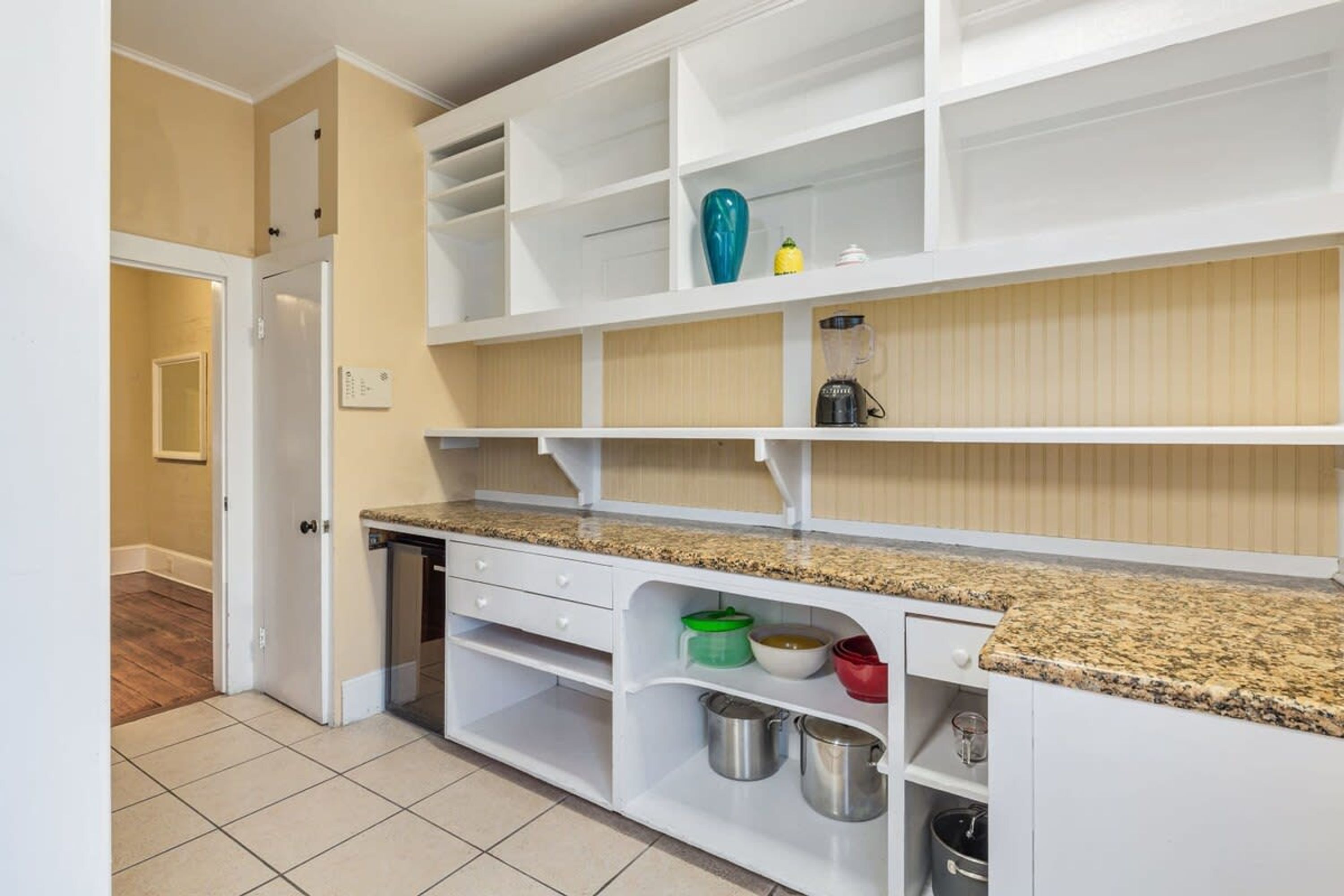 A kitchen with white cabinetry, granite countertops, and various kitchen appliances.