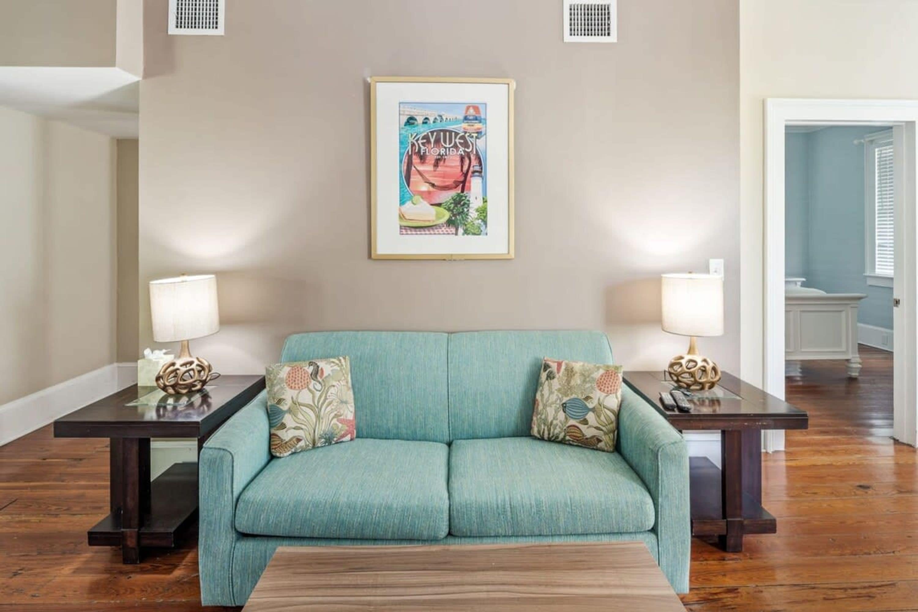 A living room with a teal sofa, two matching side tables, and a framed picture on the wall.
