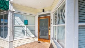 Ingresso principale con porta in legno, una cassetta postale e il numero '219' sulla parete.