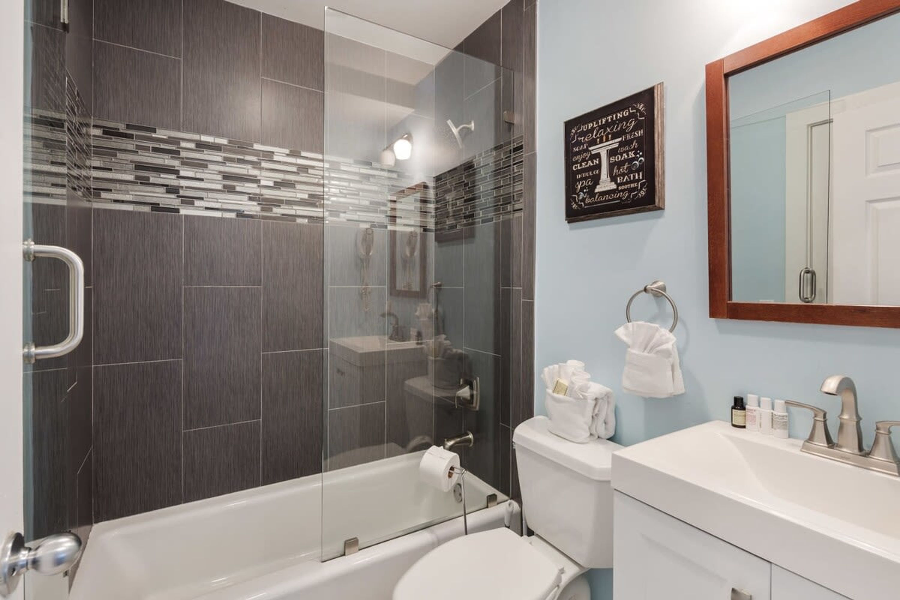 A modern bathroom with a glass-enclosed shower, a white toilet, and a vanity with a mirror.