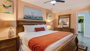 Una camera da letto con un letto, comodini, una ventola a soffitto e opere d'arte alle pareti.