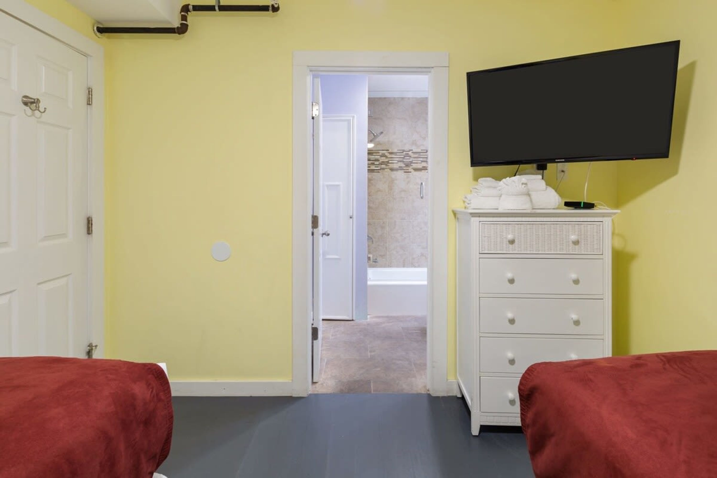 A room with a bed, a dresser, a television, and a bathroom door.