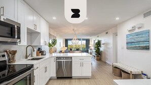 A modern kitchen with white cabinetry, a built-in oven, and a dishwasher. - Island Time Gorgeous Condo Steps To The Beach (Key West)