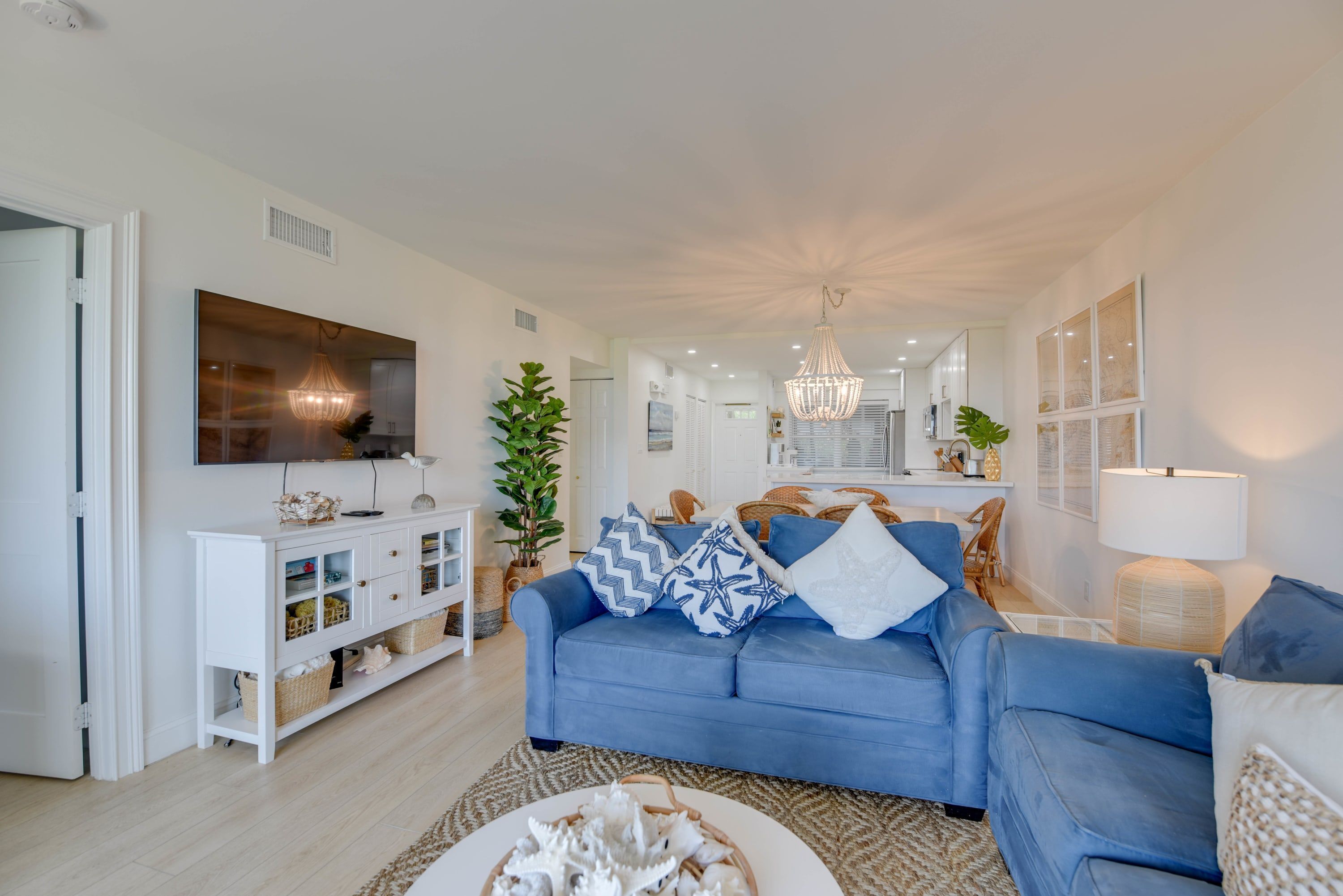 A modern living room with a blue sofa, white console, and a large TV.