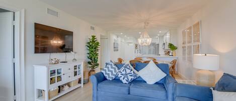A modern living room with a blue sofa, white console, and a large TV.