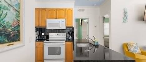 A kitchen with wooden cabinets, a microwave, an oven, and a black countertop.